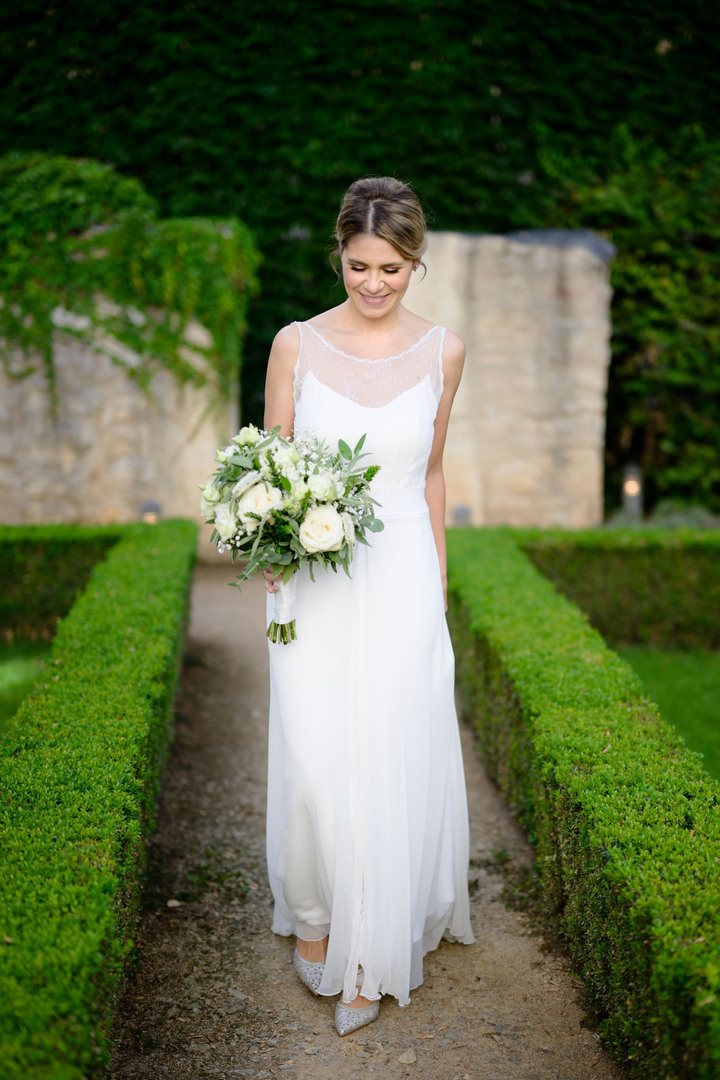 Nevěsta se usmívá, stojí v zahradě hotelu Augustine a dívá se směrem dolů.