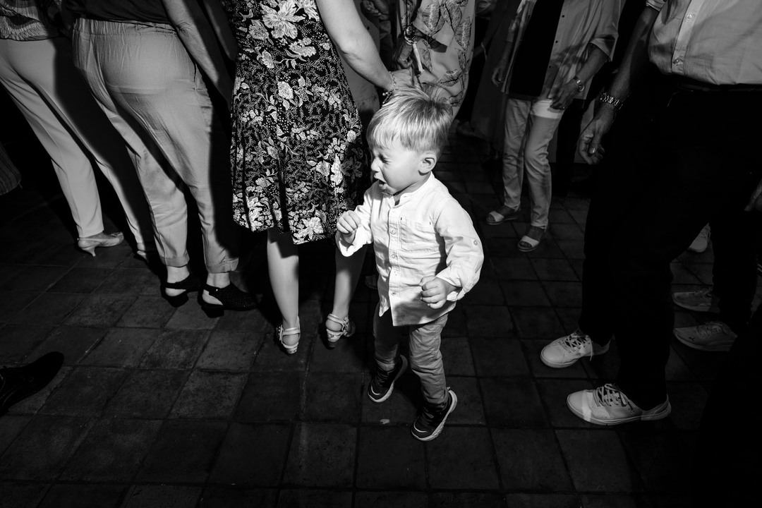 Malý chlapec si naplno užívá svatební párty mezi dospělými.