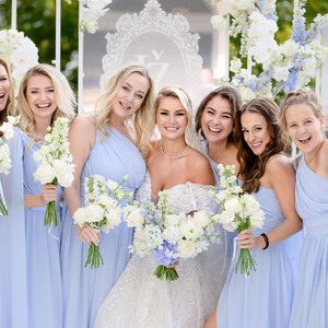 bride in white dress with bridesmaids in blue dresses holding flowers 