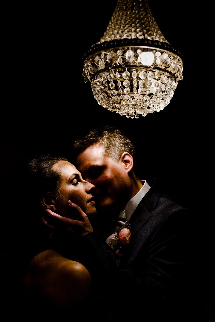bride and groom under a chandelier