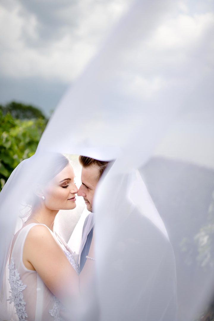 bride and groom under a veil with heavy cloud on the sky