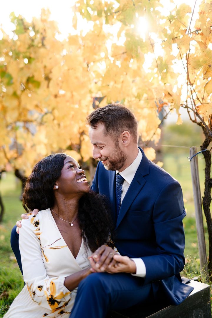 woman sitting next to a man smiling at each other with vine in a background