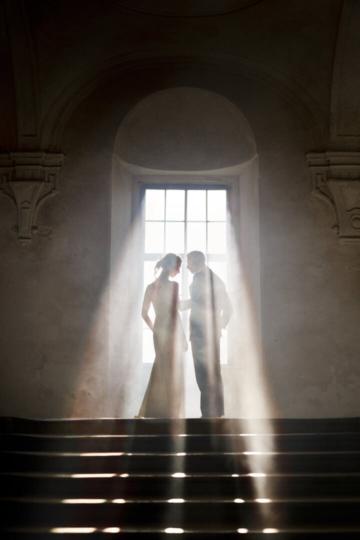 Prague bride and groom standing in the rays of light in the old monastery