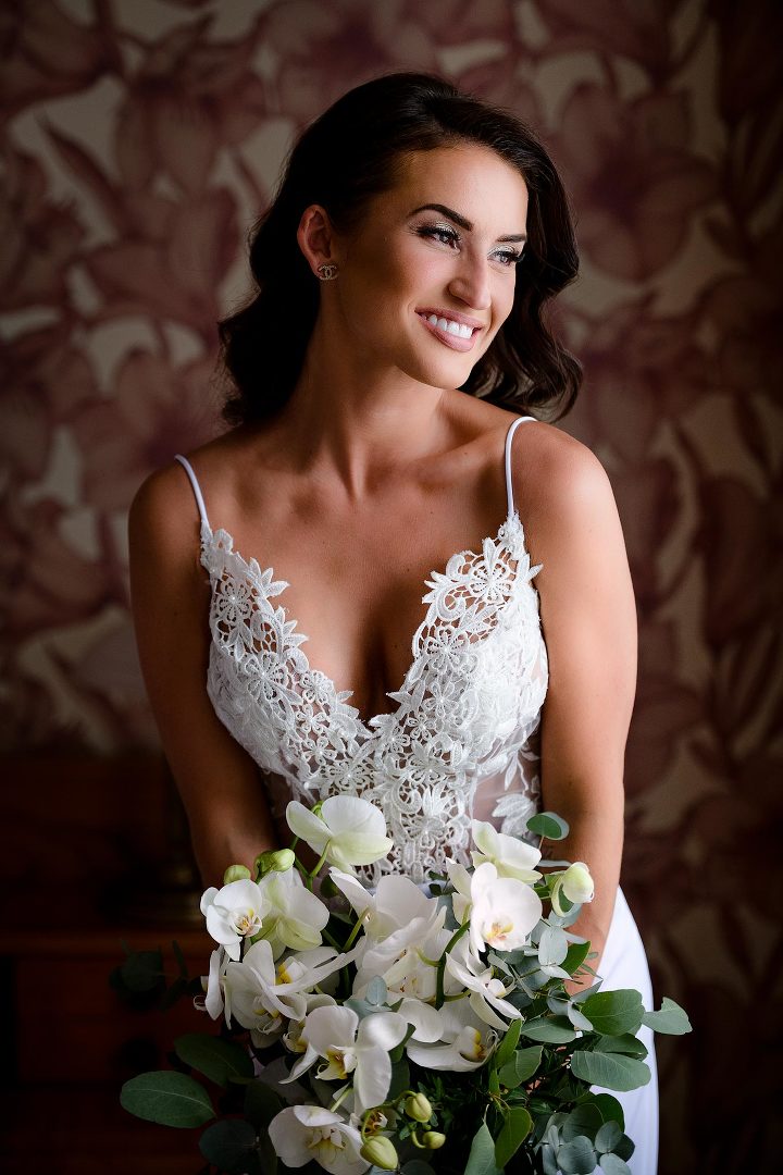 bride in a white dress holding a bouquet in a dark room