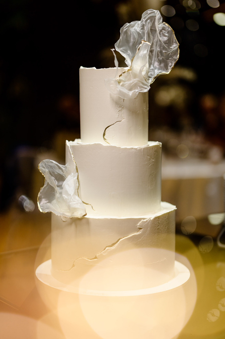 Elegant three-tiered white wedding cake with delicate floral decorations.