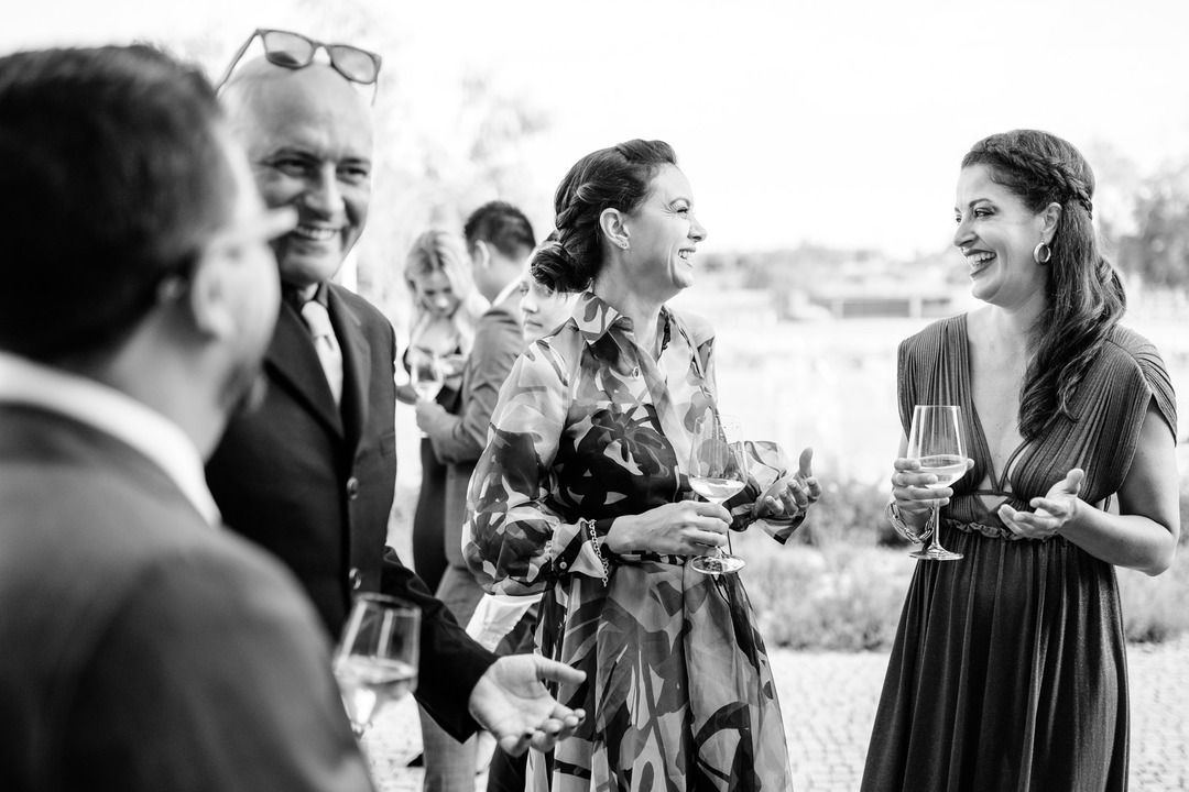 Two women with wine in hand chat and laugh joyfully.