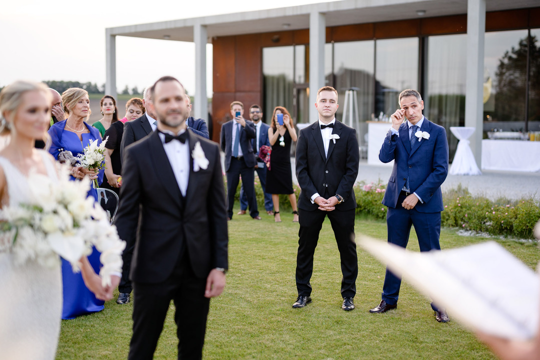 The best man is wiping his eye during the ceremony, possibly crying.