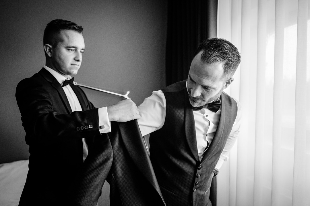 Groom getting help with his jacket from a friend before the wedding at Obelisk Winery.