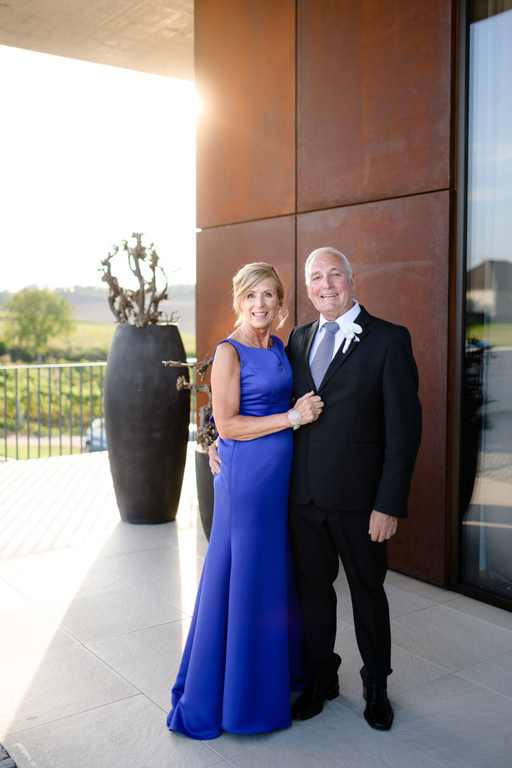 The groom's parents pose for a photo in front of the Obelisk Winery.