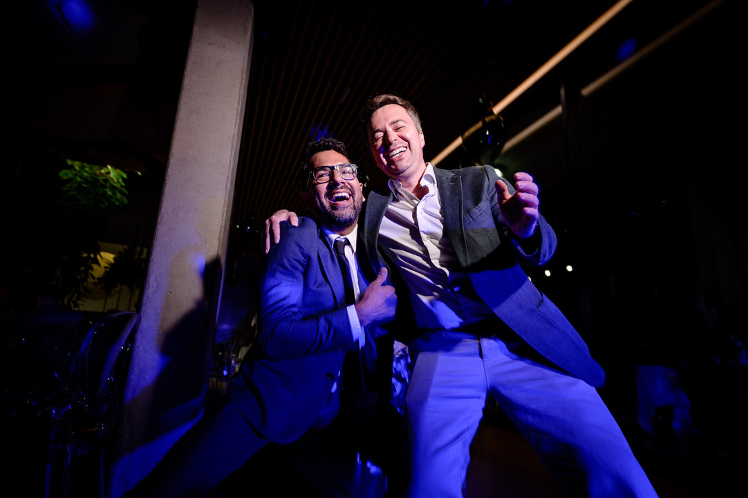 Two men pose together on the dance floor, laughing joyfully.