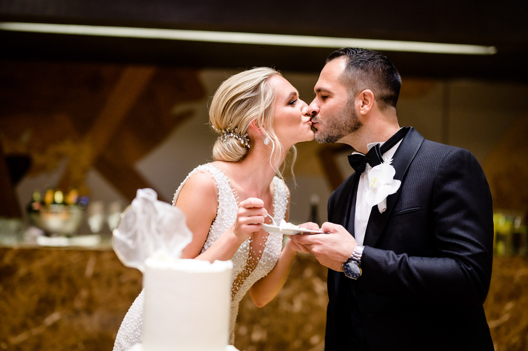 Newlyweds sharing a romantic kiss while cutting the cake