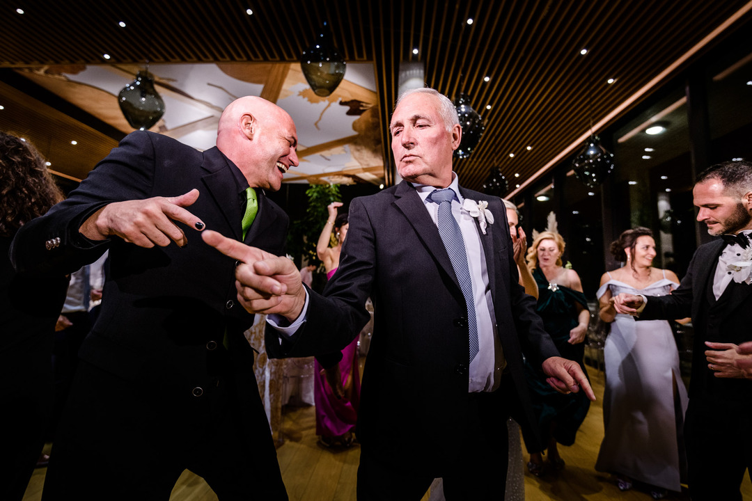 Two men are dancing seriously on the dance floor, playfully pretending.