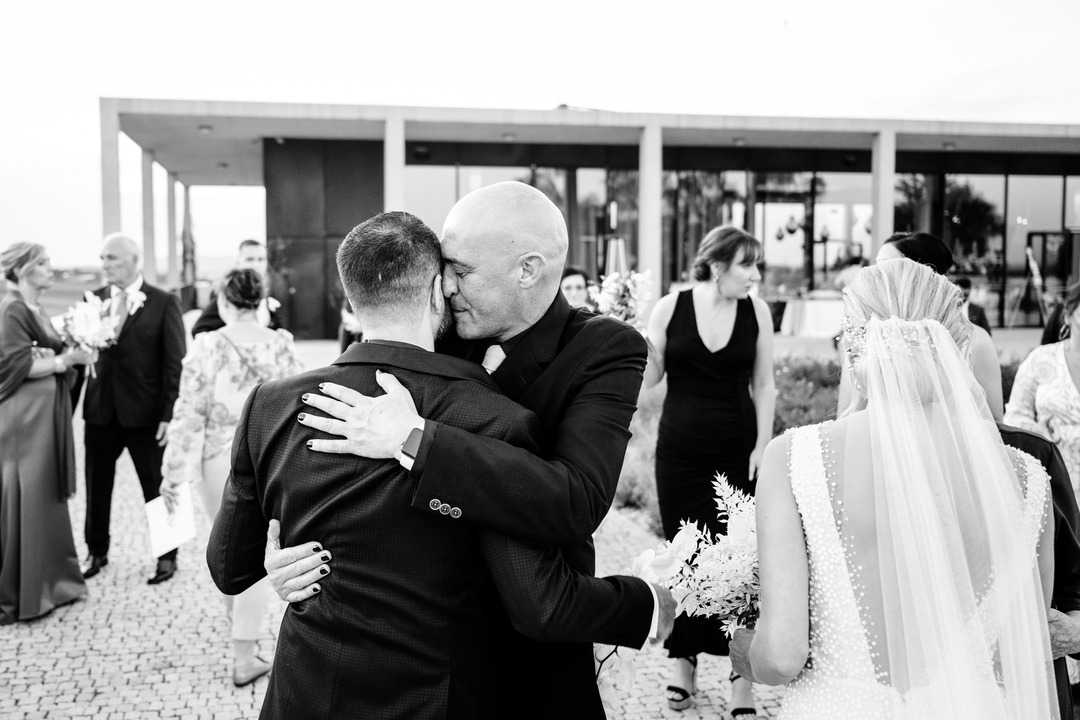 The groom's friend hugs him, and it's noticeable that his nails are painted black.