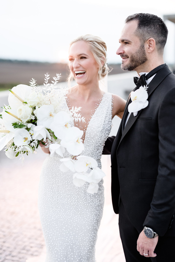 A shot of the wedding couple hugging from behind, with the bride laughing warmly.