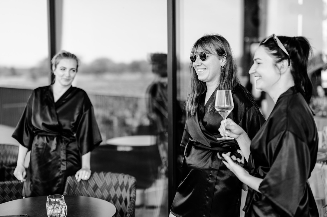 The bridesmaids sip wine and laugh together before the ceremony.