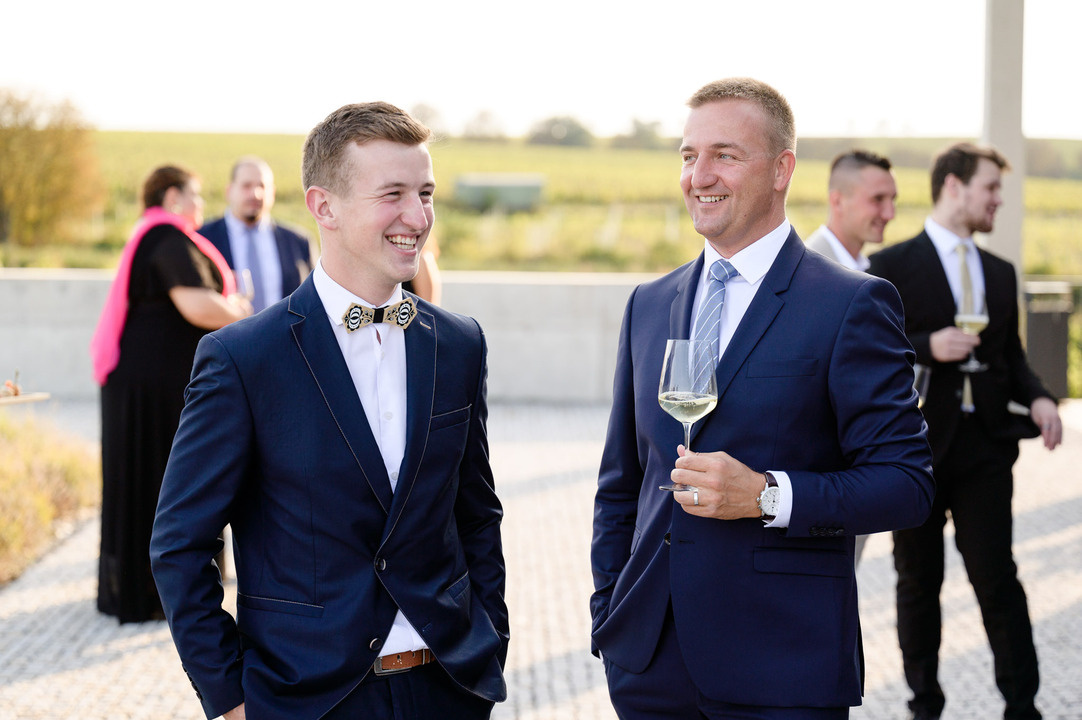 Two men in blue suits happily chat during a calm moment before the ceremony.