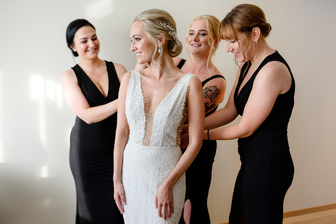 Bride in a stunning gown surrounded by bridesmaids in elegant black dresses at the Obelisk Winery wedding.