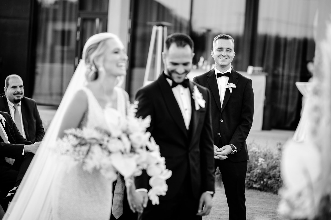 A shot of the bride, groom, and best man, all three smiling.