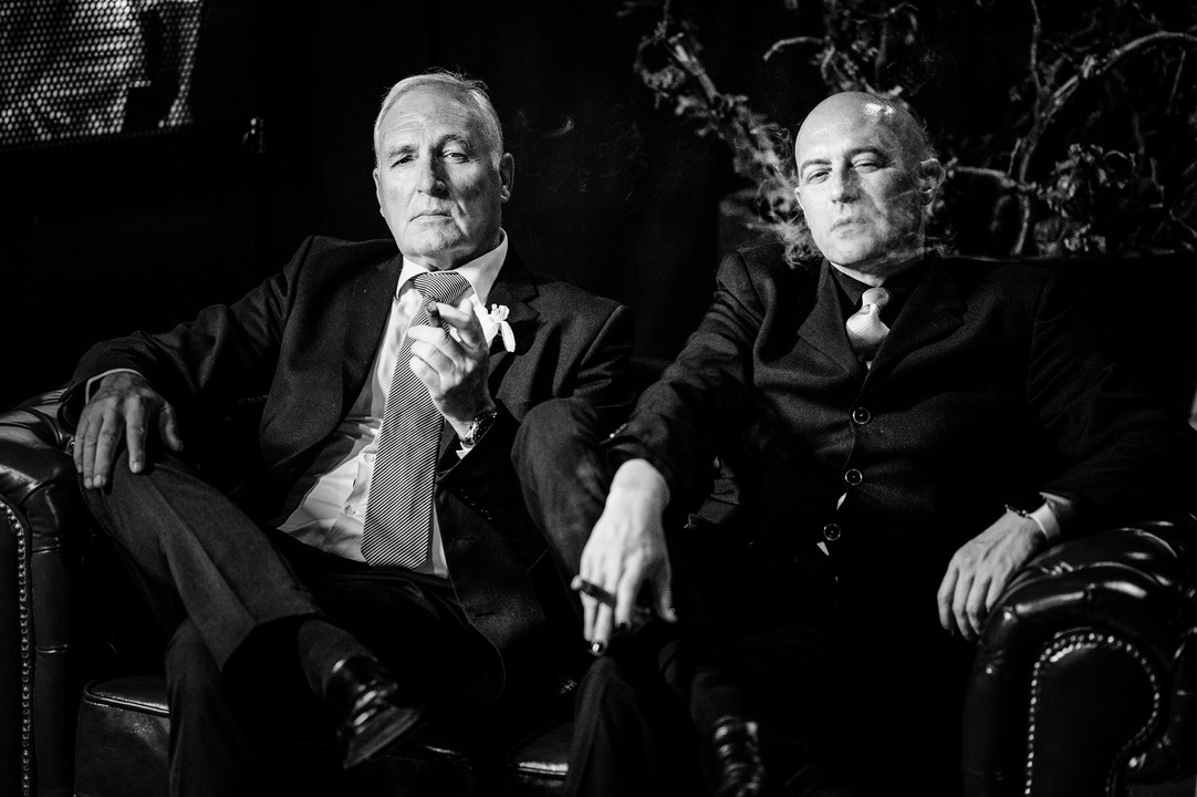 Two men in suits sitting and enjoying a moment together with cigars 