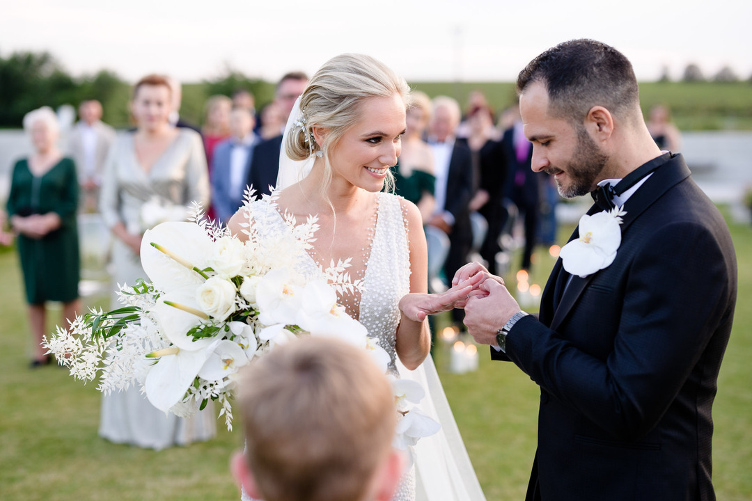 Groom placing the ring on the bride's finger during their wedding ceremony.