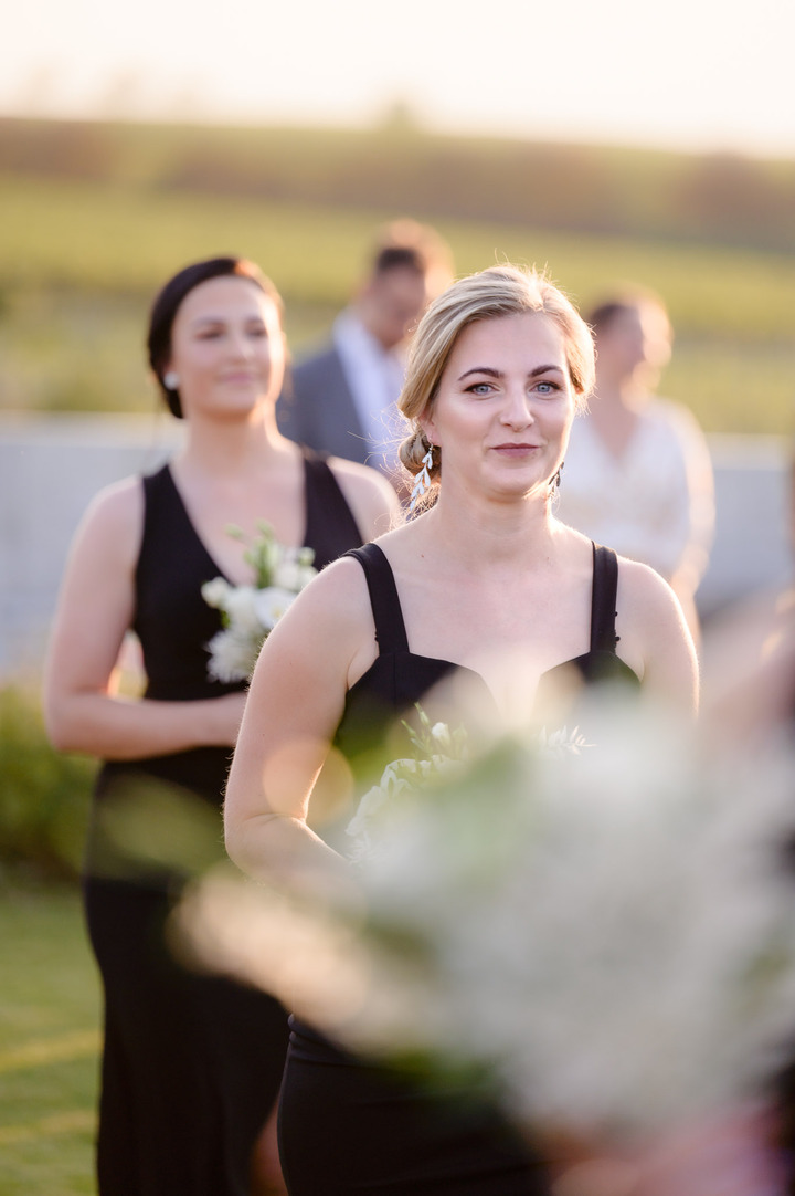 Bridesmaid in elegant black dresses walking down the aisle at Obelisk and smile.