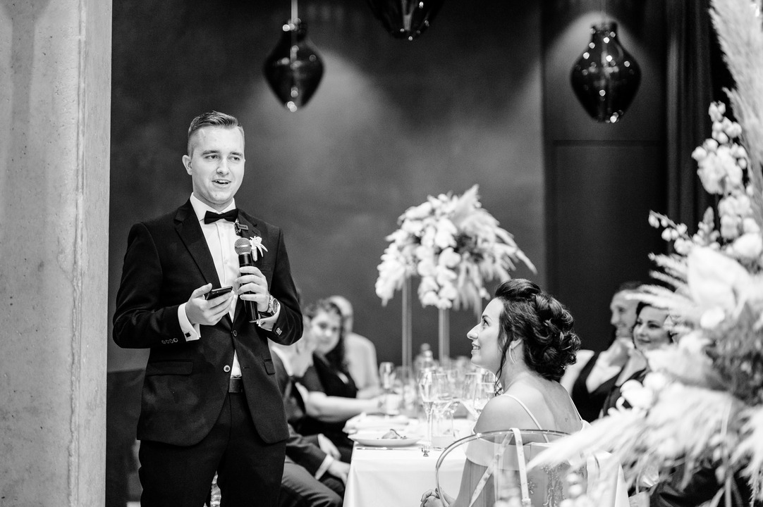 The groom's friend is giving a speech, the photo is black and white.