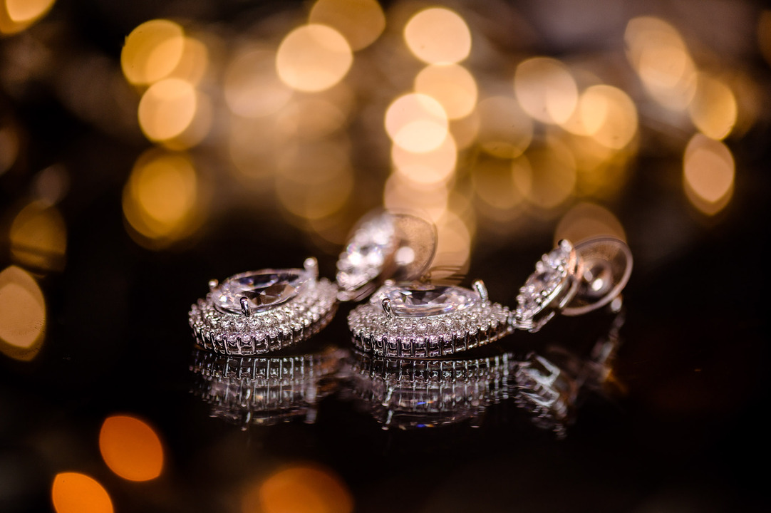 Close-up of sparkling wedding earrings set against a bokeh background of golden lights.