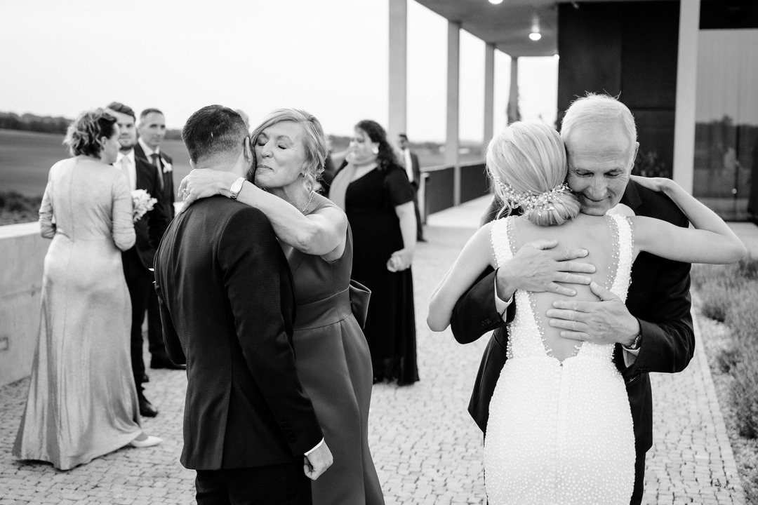 The groom's parents happily hug and congratulate the newlyweds.