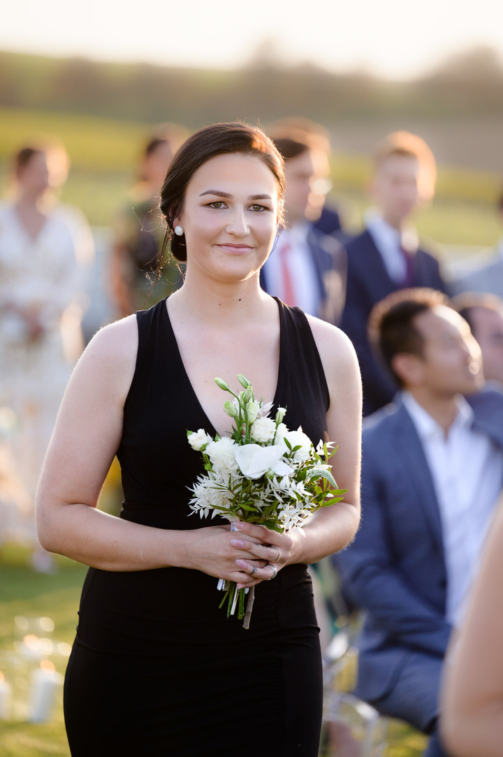 Detail on bridesmaid in black dresses holding bouquet and smile.