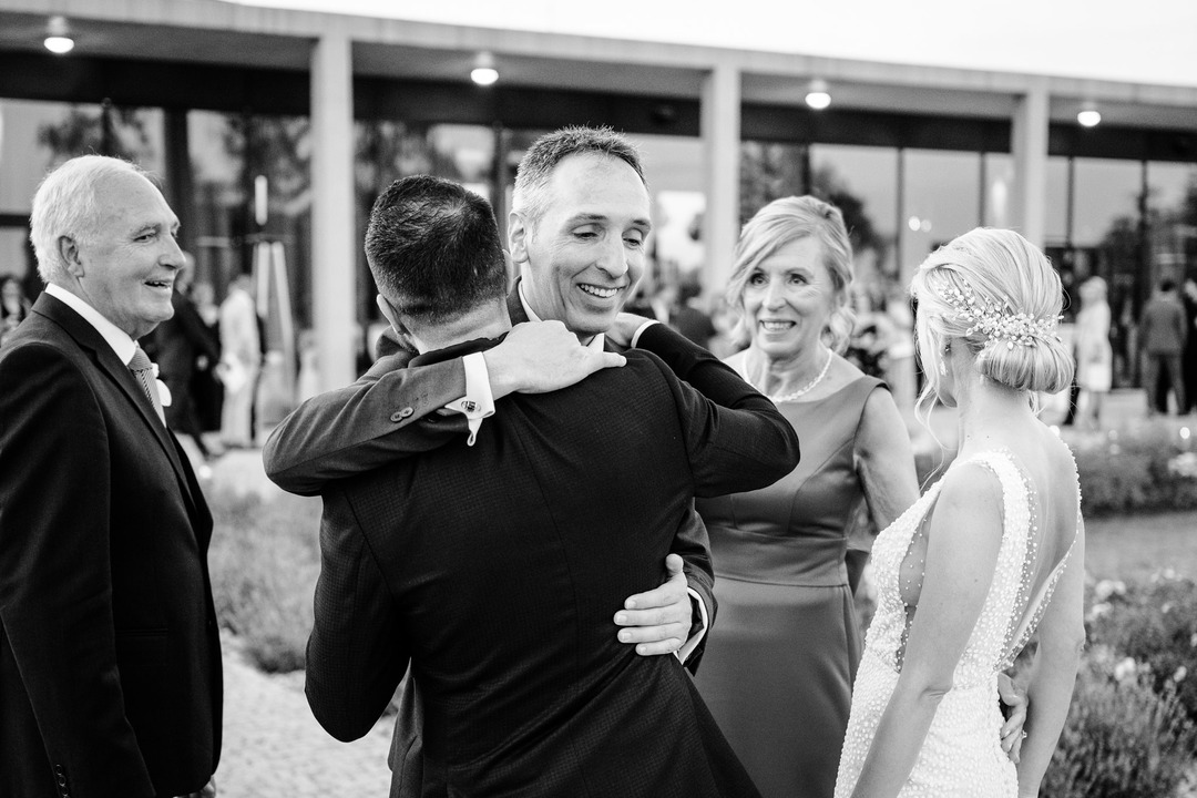 The groom's brother excitedly hugs his brother, the groom.