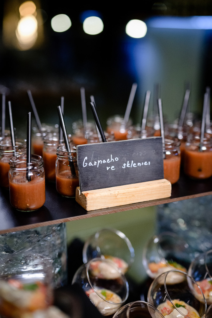 Polévka Gazpacho podávaná ve sklence s brčky na večerní recepci.