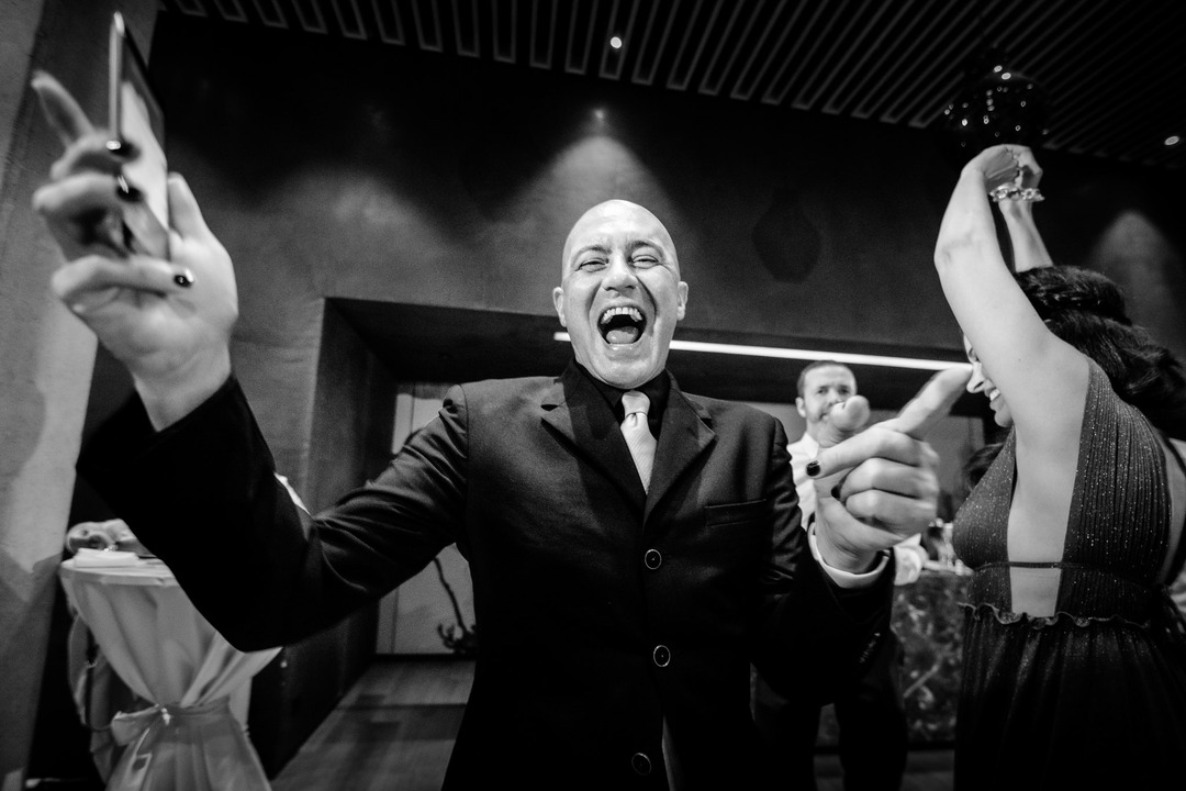 A black-and-white photo of a bald man smiling brightly directly at the camera.