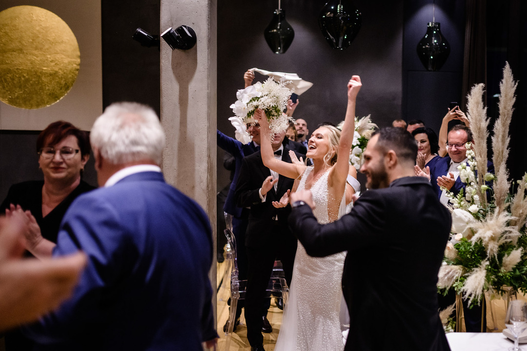 The newlyweds walk among the guests, with the bride raising her arms in joy.