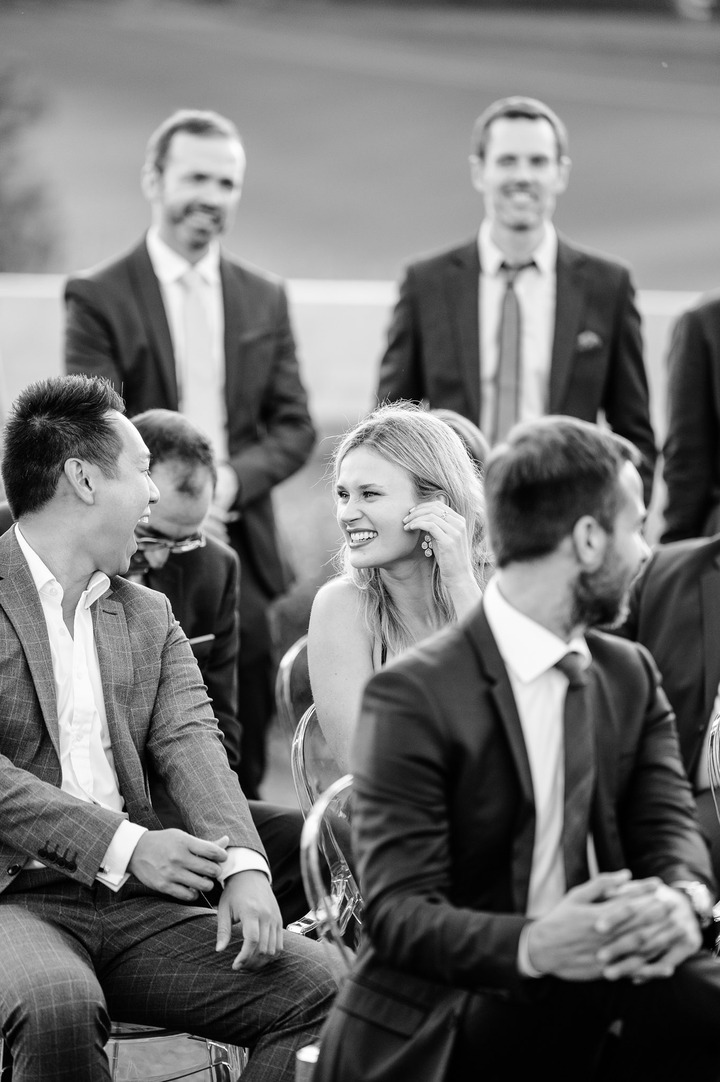 A black and white photo showing a shot among the guests, two of them looking at each other and laughing heartily.