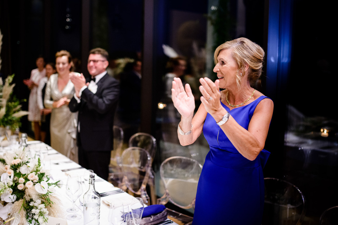 The groom's mother applauds joyfully during a wedding celebration at Obelisk Winery.