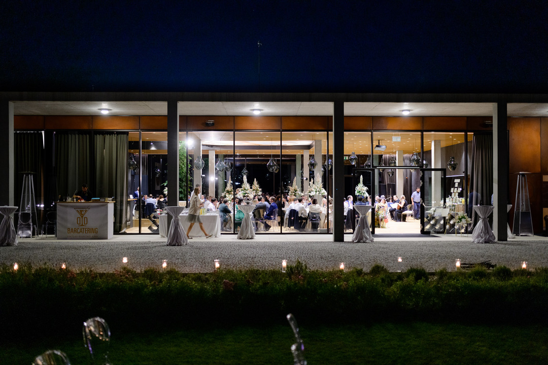 Guests enjoying the wedding reception at Obelisk Winery, visible through the venue's glass windows. 