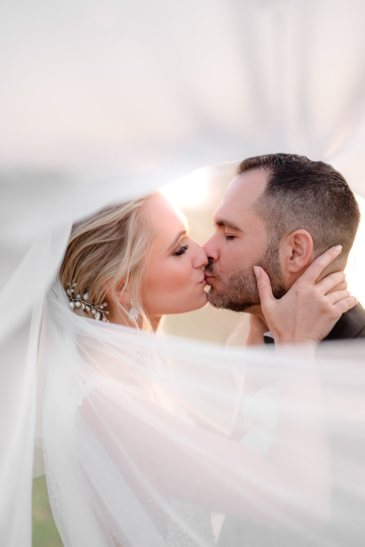  Bride and groom sharing a tender kiss under the bride's veil at Obelisk Winery.