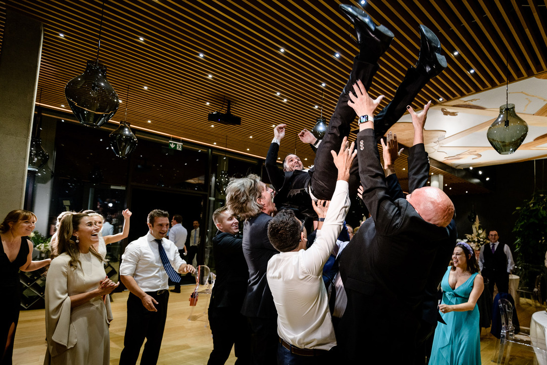 Guests joyfully lift the groom during a lively wedding reception at Obelisk 