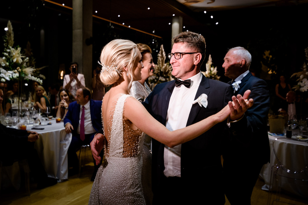 The bride dances with her father, who smiles at her.