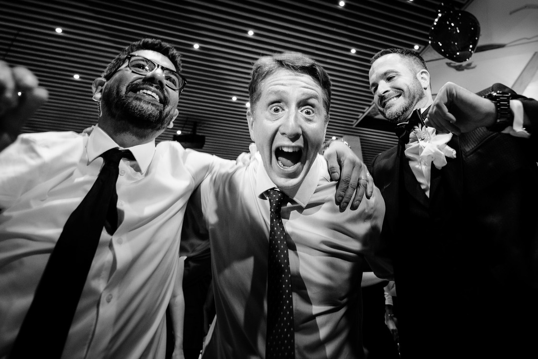 Two men on the dance floor embrace each other, one excitedly shouting into the shot.