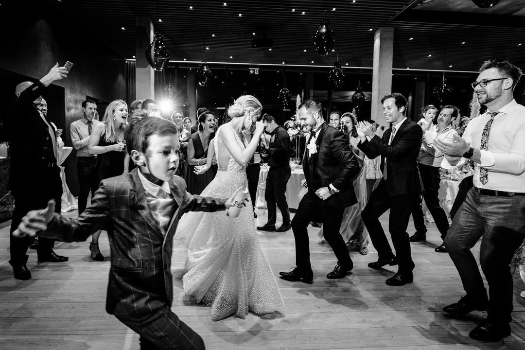 The newlyweds lead the crowd in a joyful dance, their guests cheering and clapping along.