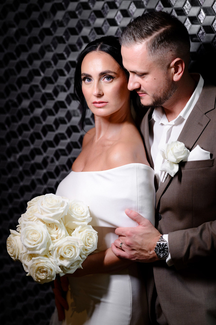 The groom hugs his wife from behind, leaning into her, the photo radiating a passionate atmosphere.
