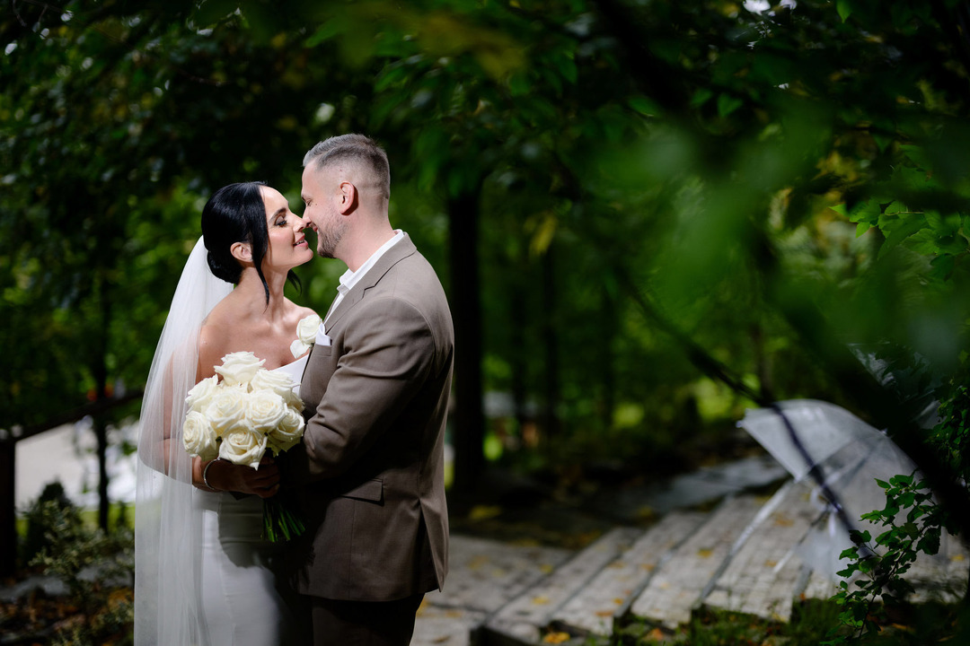 The newlyweds are about to kiss, standing in the garden of Villa Cattaleya, the bride holding a bouquet of white roses.
