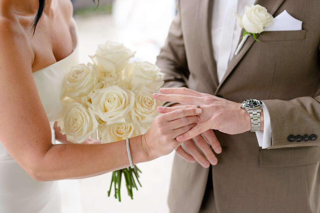 A close-up of the bride placing the wedding ring on the groom's finger during the ceremony.
