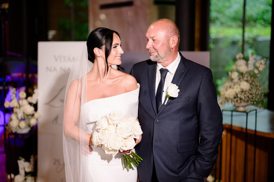 Black and white photo of the bride and her father smiling at each other and sharing a hug.
