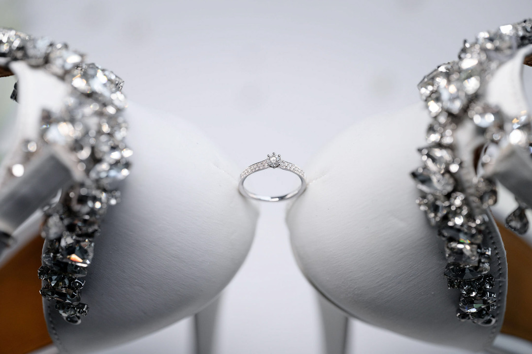 The engagement ring nestled between the bride's white ceremonial shoes.
