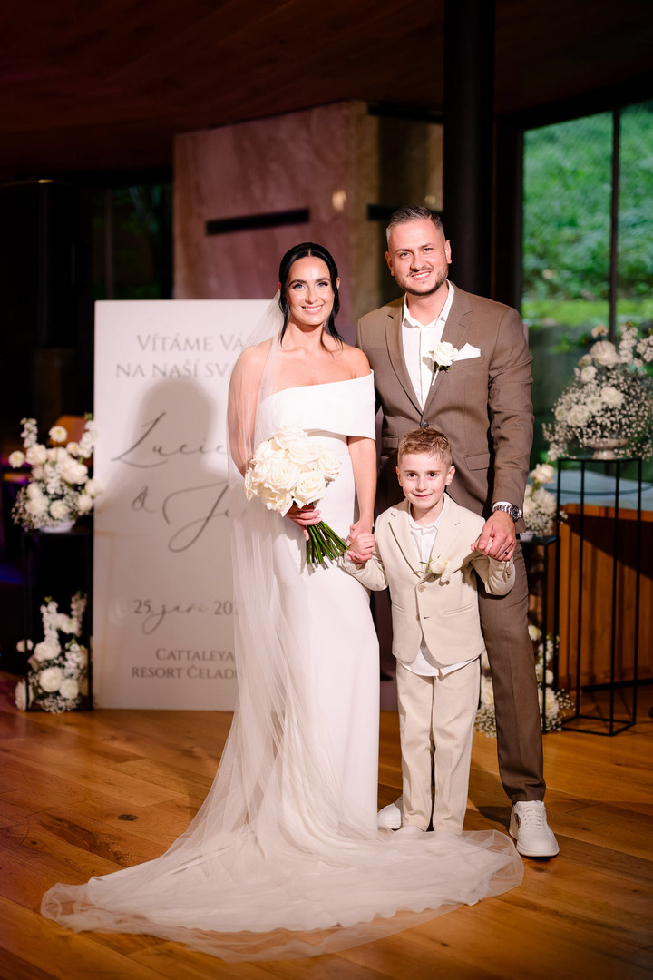 The newlyweds are photographed with their son, each holding one of his hands, all smiling happily at the camera.
