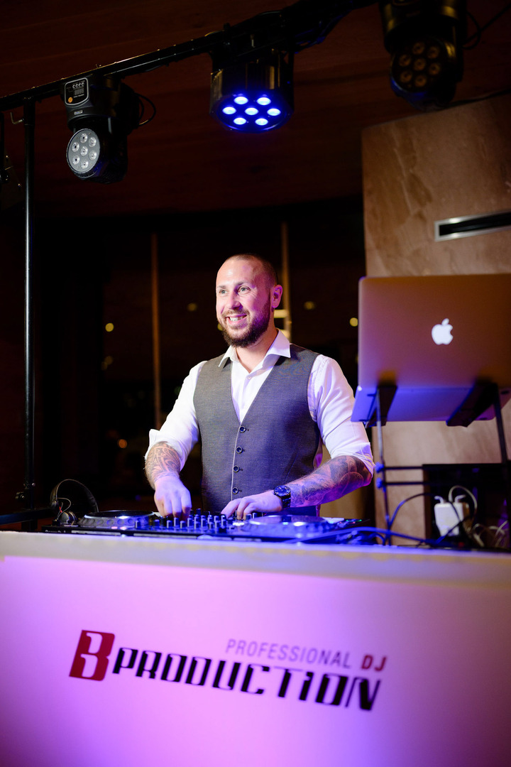 The DJ behind his booth is creating a laid-back atmosphere, bathed in purple lighting.
