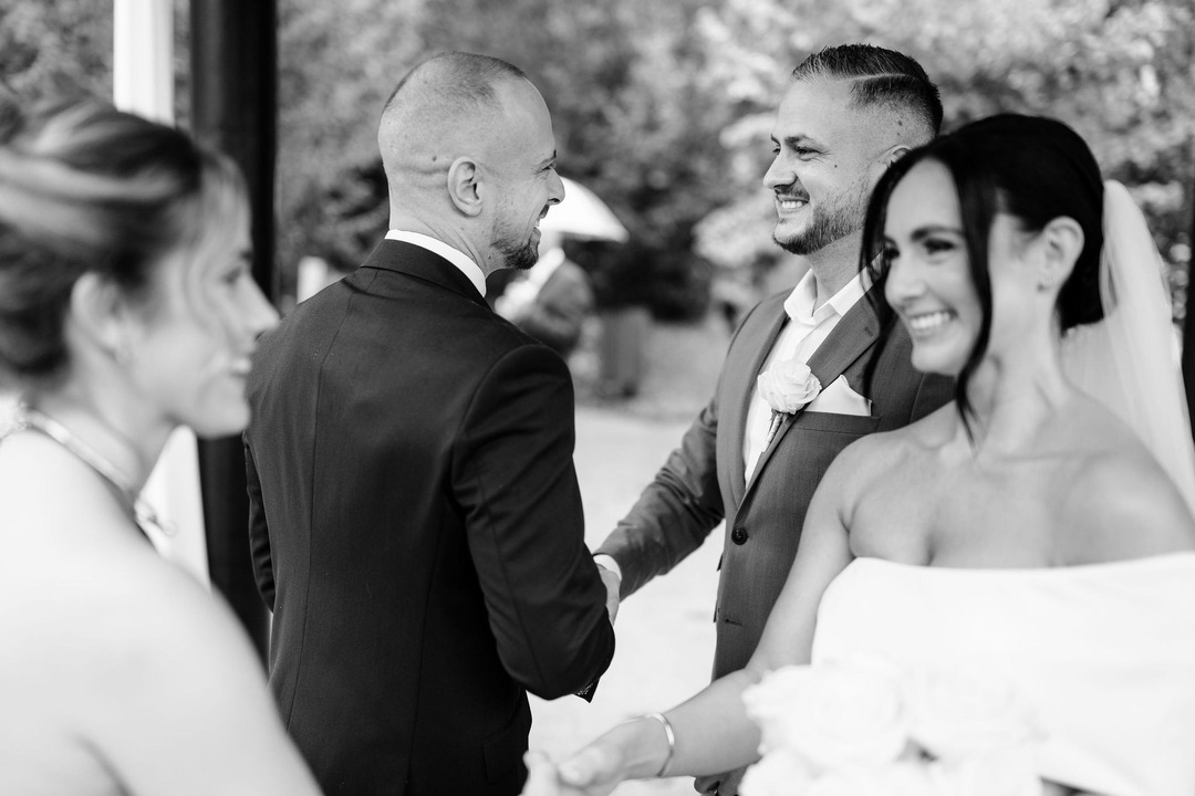 Black and white photo of the best man wishing the groom all the best in his married life.
