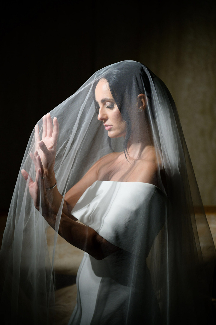 Bride in a moment of calm and elegance, adjusting her delicate wedding veil at Villa Cattaleya